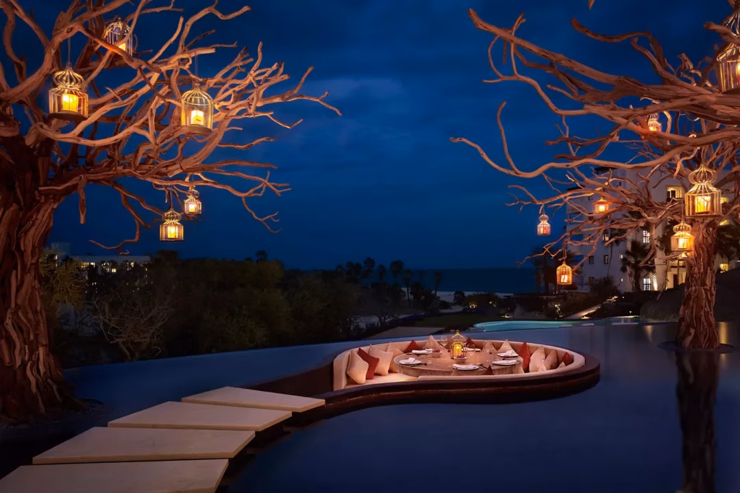 Curved oceanfront resort pool at golden hour with the Sea of Cortez beyond, Las Ventanas al Paraíso lifestyle, Los Cabos
